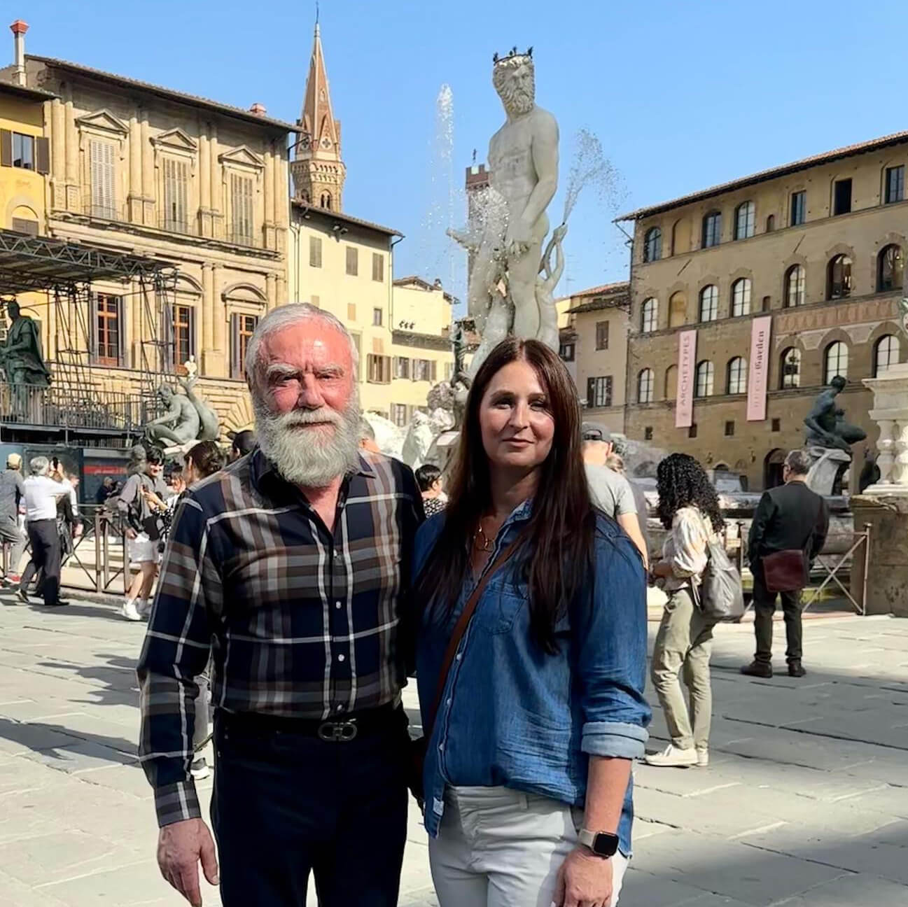 Posing in front of The Fountain of Neptune in Florence, Italy, Amanda and Emil DiIorio face the camera with one arm around the other.