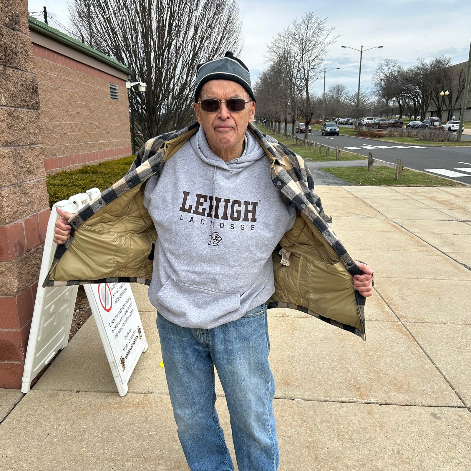 Dick Johnson stands on the sidewalk, holding his jacket open to show off his Lehigh shirt.