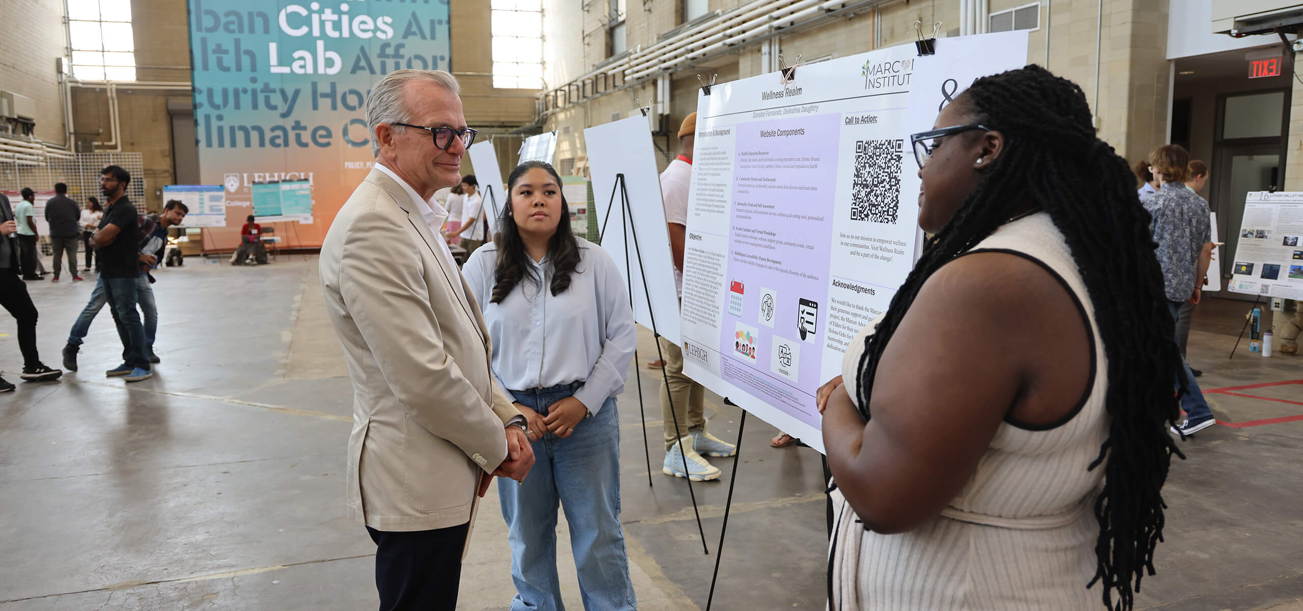 Alumnus stands in front of a student whiteboard presentation as a judge at the 2024 summer research expo.