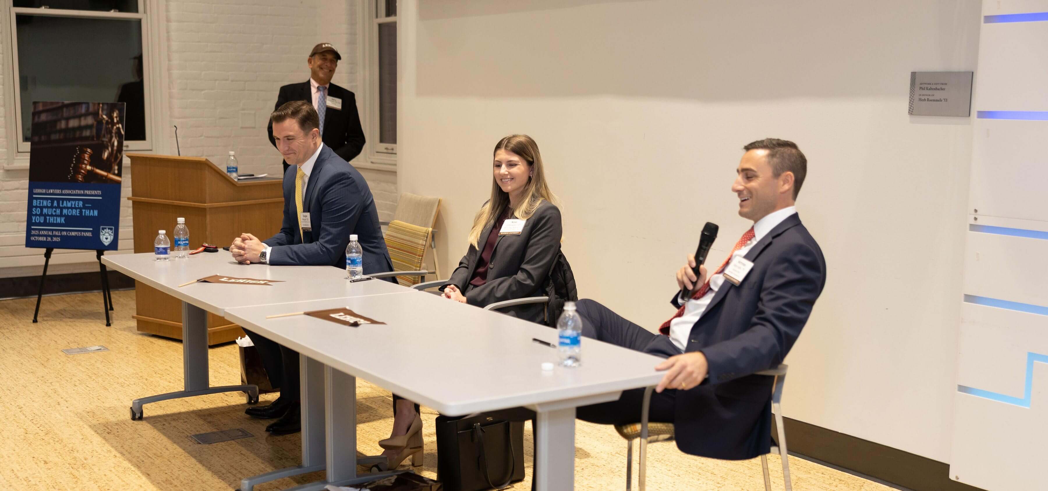 Doug and two other Lehigh Lawyers alumni sit at a panel in front of a room full of students and smile