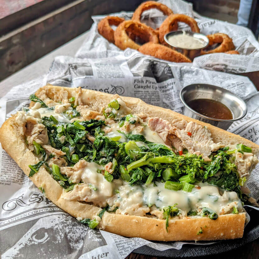 Roast pork with broccoli rabe and cooper sharp cheese with a side of au jus and onion rings