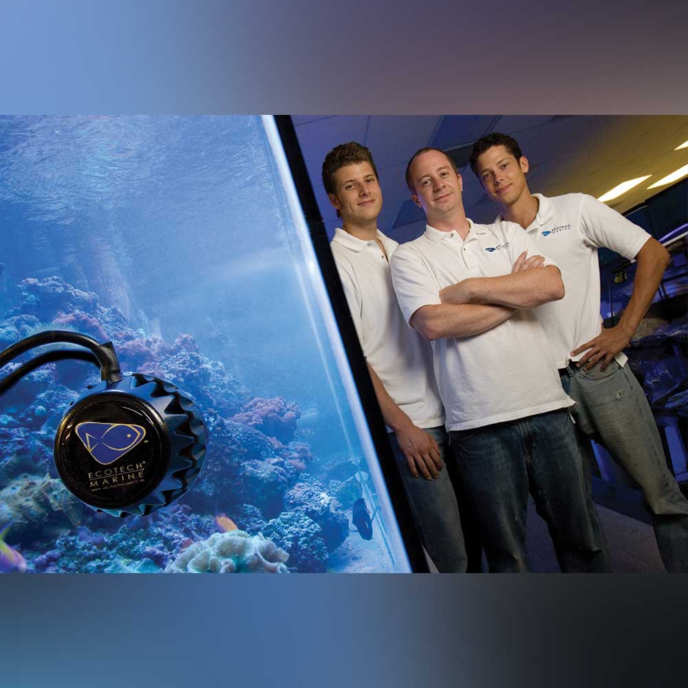 Patrick stands with two other men alongside an aquarium using a VorTech propeller pump. They wear EcoTech Marine shirts.