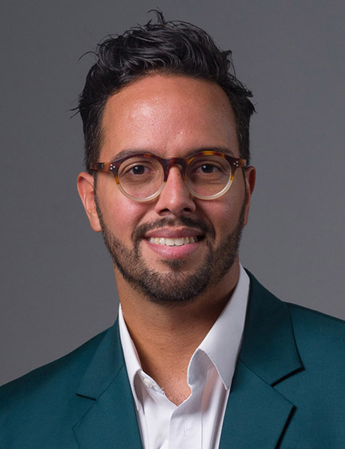 Eddie Guerra wears a sport coat and glasses