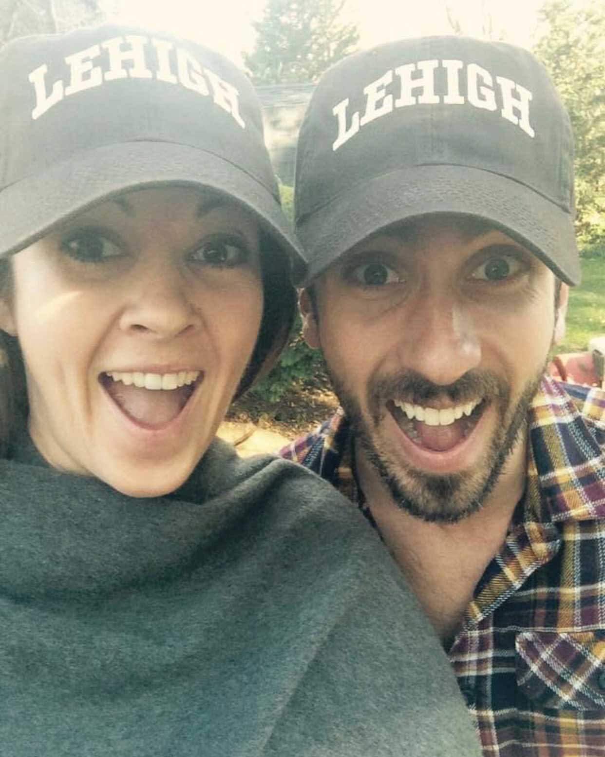Emily and Cannon smile widely while wearing matching brown Lehigh hats. Cannon wears a plaid shirt and Emily a gray sweater.