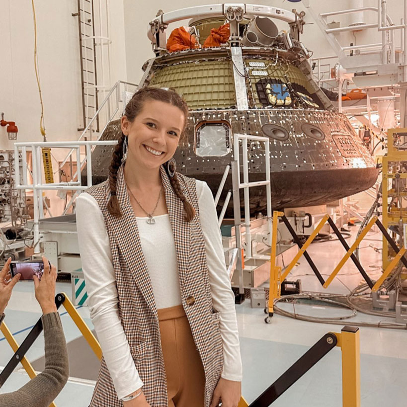 Emma O’Rourke posing before a command module while engineers work