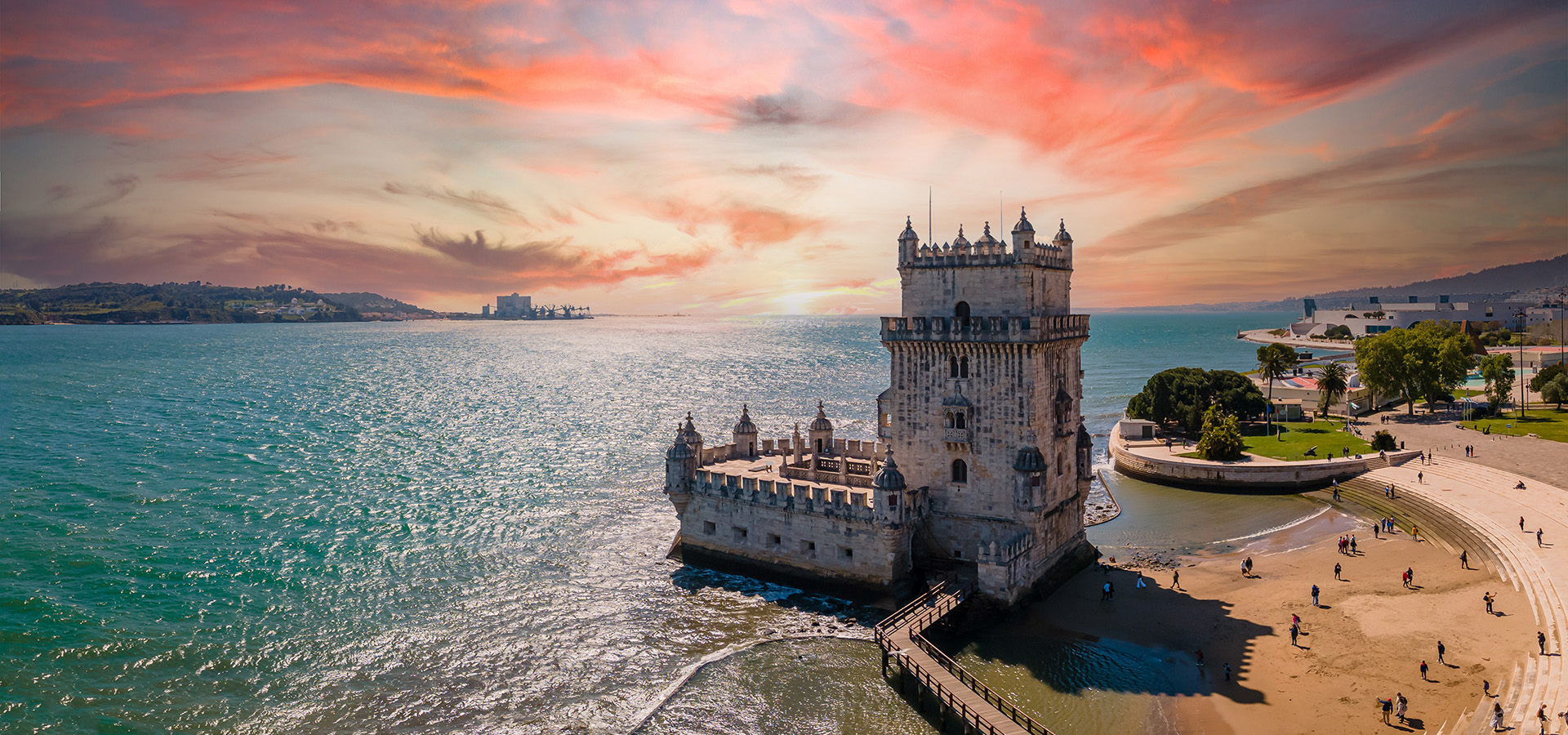 A castle sits on the coast before a brilliant sunset.