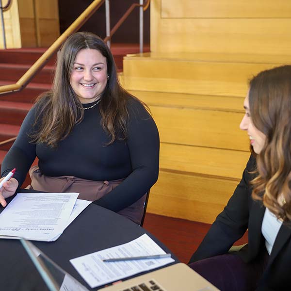 Alumna smiles at student she helps