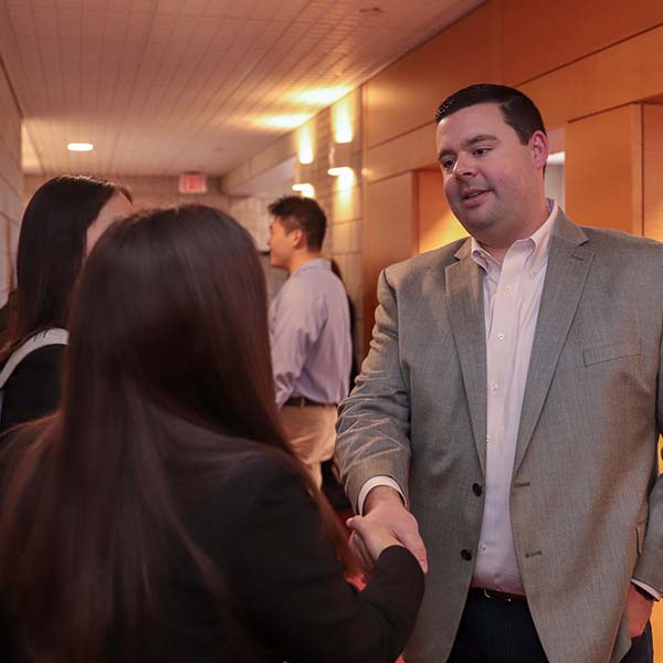 Alumnus shakes hands with a student