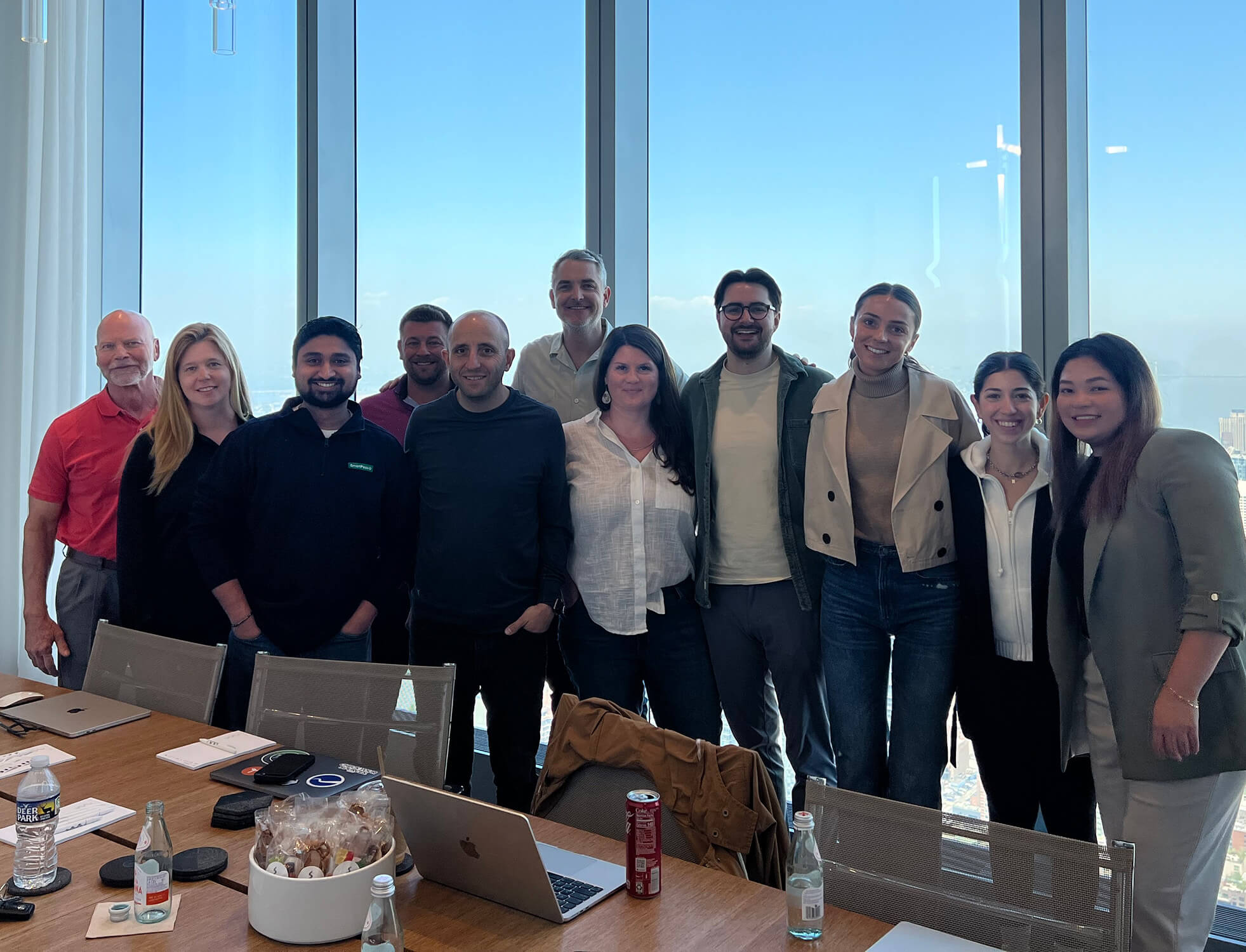 Peter Luba and SmartPass team stand in front of a large glass window for a group photo