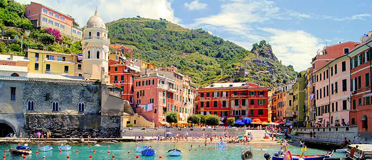 A Scenic view of Cinque Terre National Park beach with colorful old buildings against a backdrop of a green rugged mountain