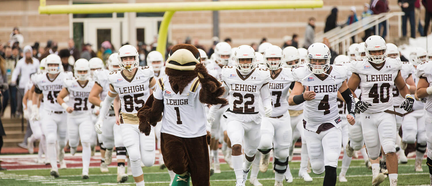 Lehigh mascot Clutch leads the football team onto the field.