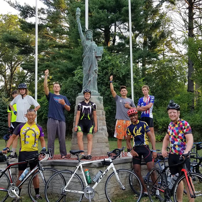 Gary Pan poses with the Scouts who biked across the US, standing in front of a replica of the Statue of Liberty