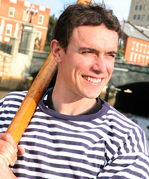 Matthew Haynes holds an oar and smiles