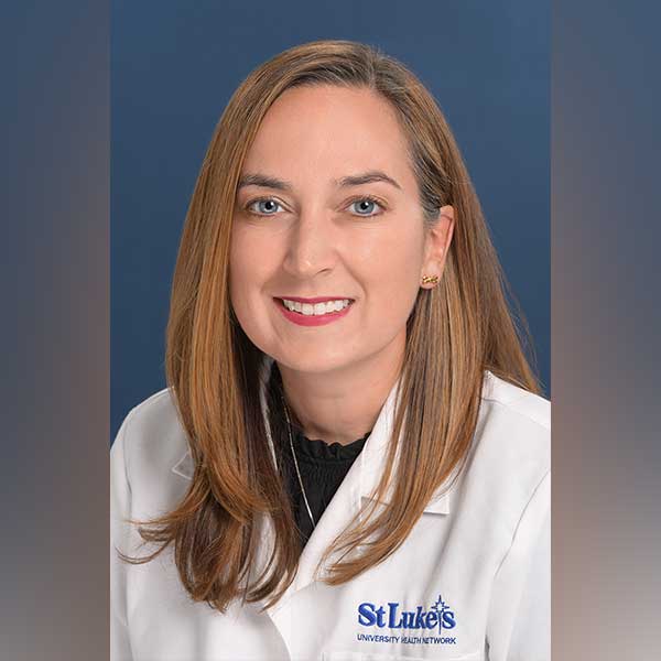 Hannah smiles while wearing her St. Luke's white coat