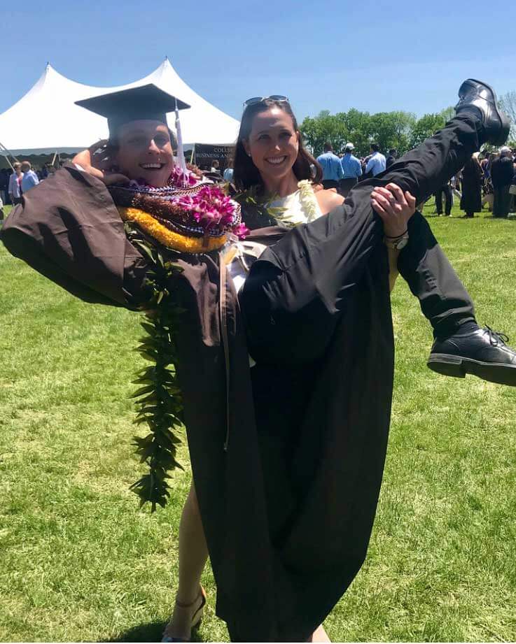 Sarafina picks up Santana after graduation. Santana wears his cap, gown, and several leis. Sarafina wears a white dress.
