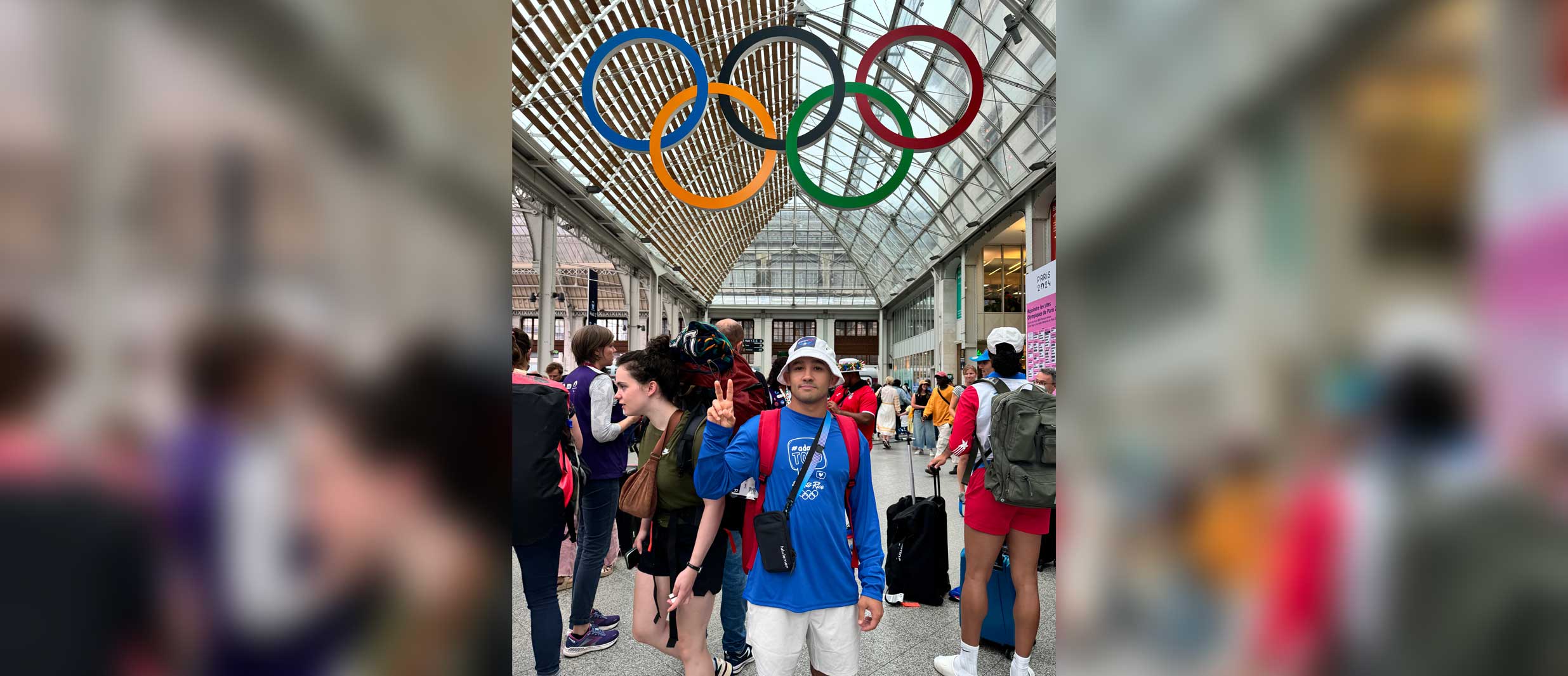 Darian Cruz standing beneath the overlapping rings of the Olympics.