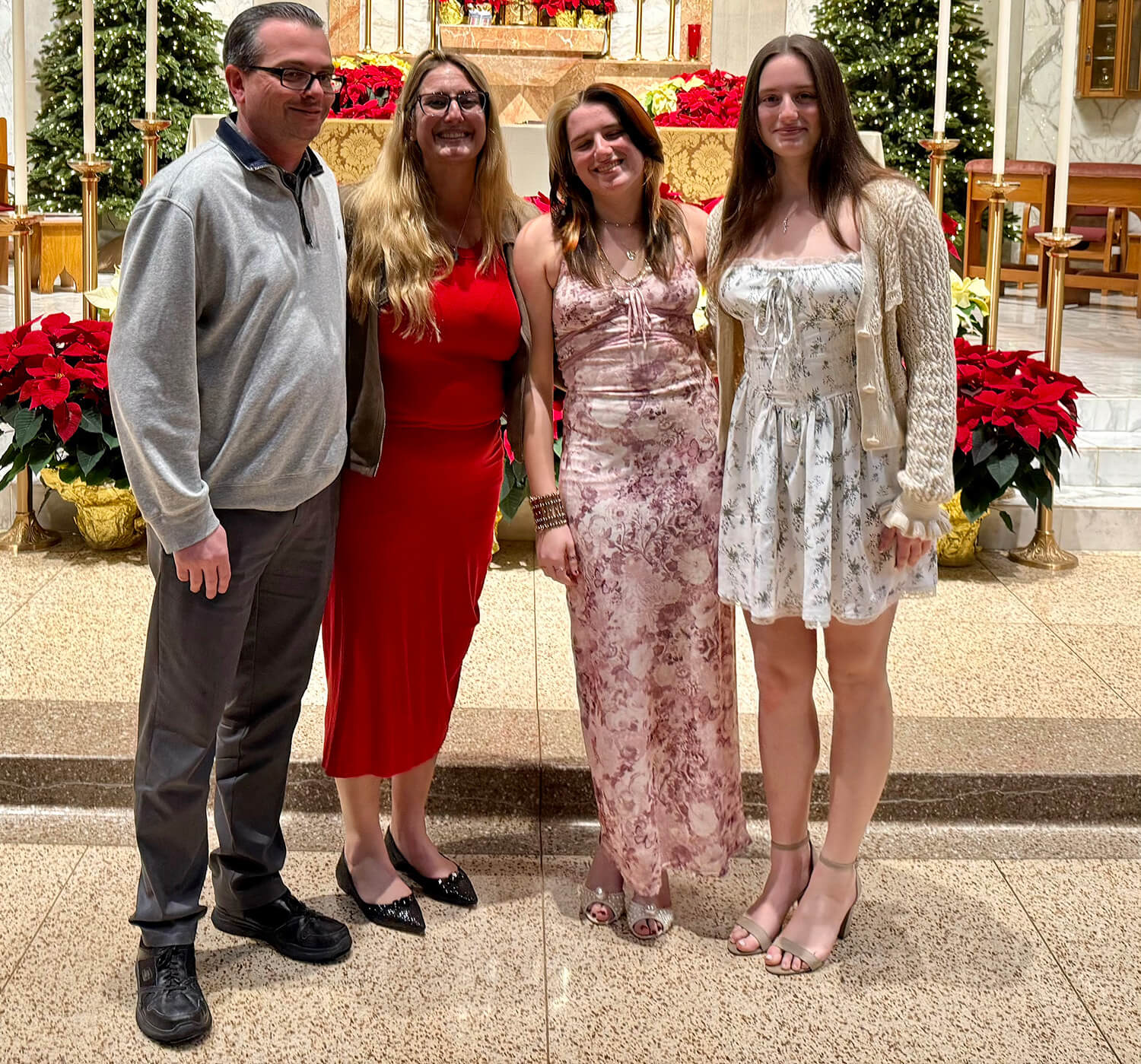Rochelle Sheridan and Patrick Sheridan stand at a church altar decorated for Christmas, posed with 2 teenage daughters.