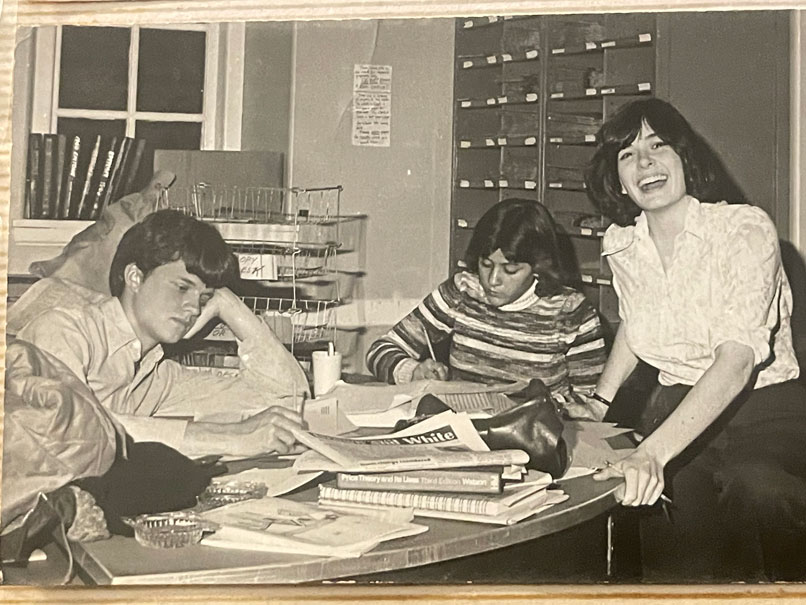 A young Dennis Sprick sitting and working on The Brown and White newspaper with two other people at the table