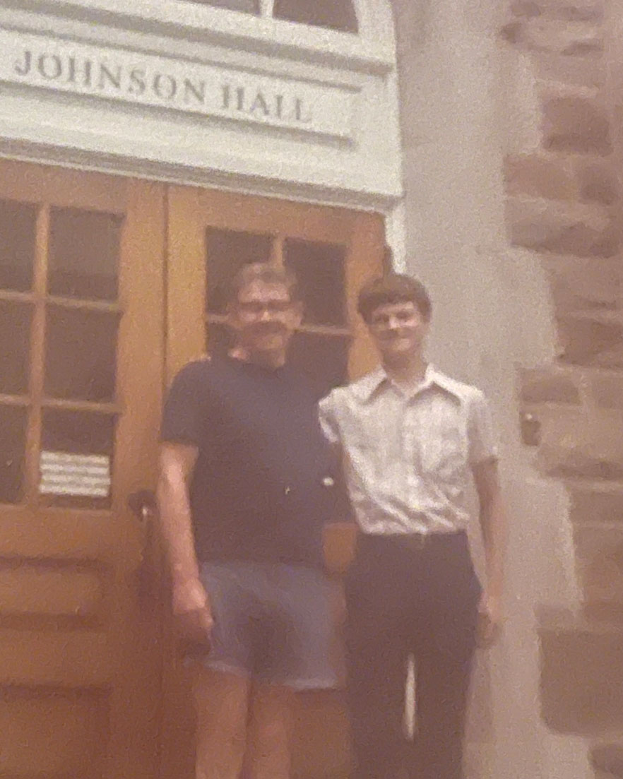 A young Dennis Sprick standing posing with an older gentleman on the doorstep of Johnson Hall
