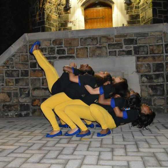 Five people lean backwards onto each other demonstrating how sorority members are one another's keepers.