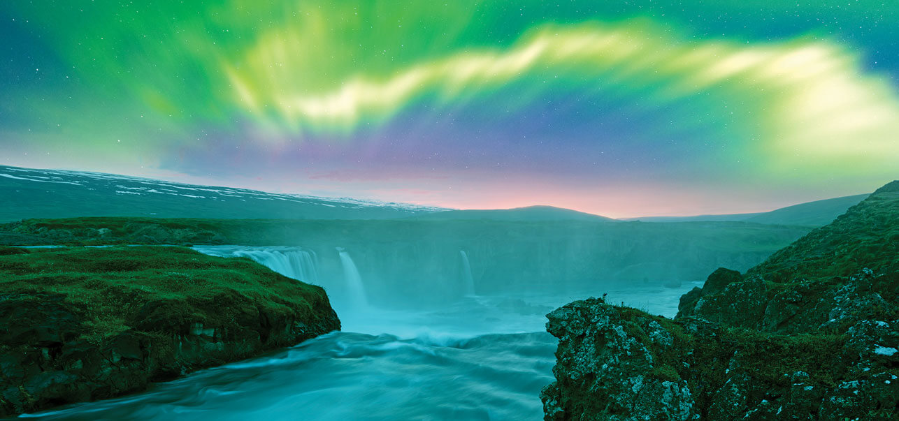 Vibrant northern lights appearing over a waterfall in Iceland.