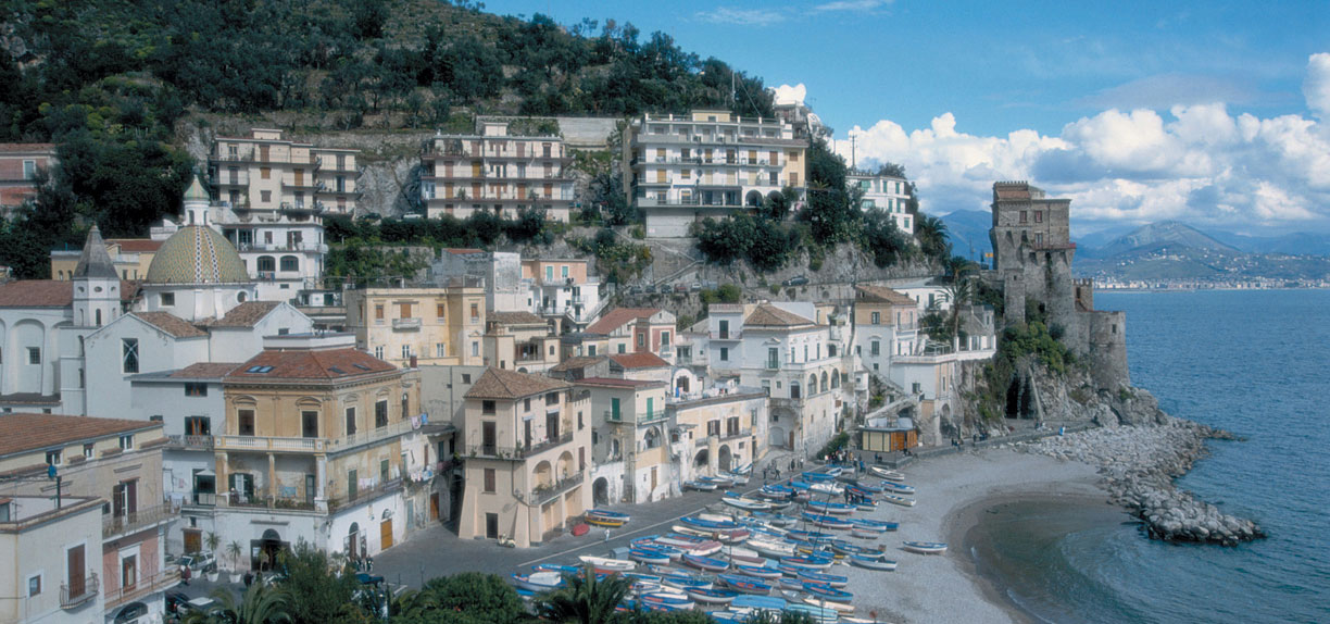 Buildings lining the Amalfi Coast while boats are piled on the beach.