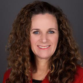 Jennifer Nelson smiling for a photo while wearing a red blazer