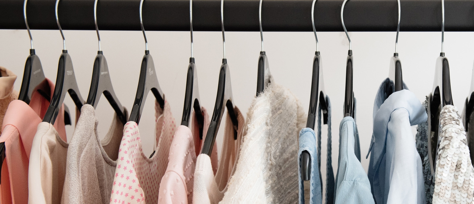 A close up of a colorful assortment of women’s shirts on black hangers.