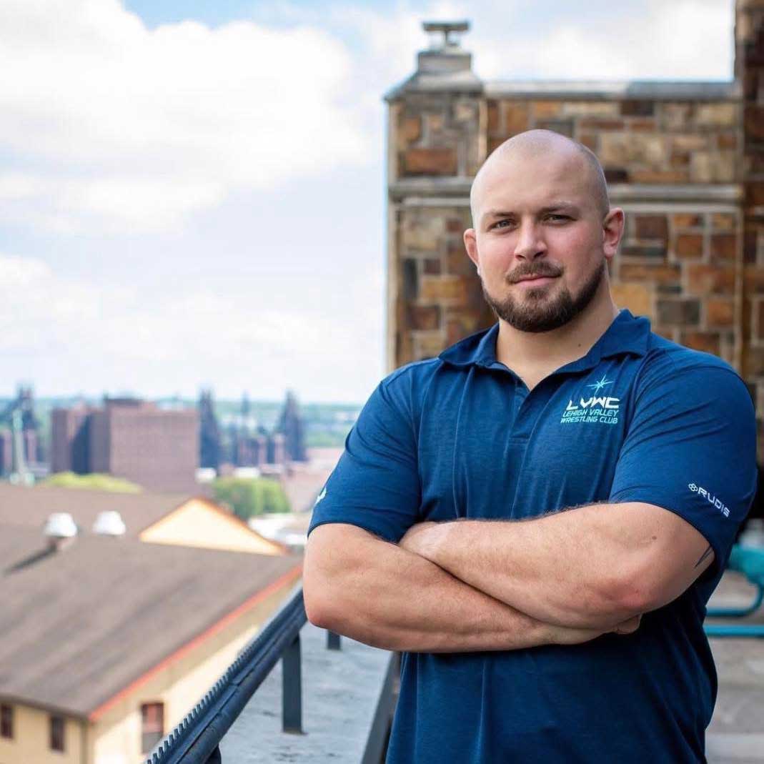 Wood crosses his arms in front of his chest while posing on Lehigh's campus. He wears a blue Lehigh Valley Wrestling Club top.