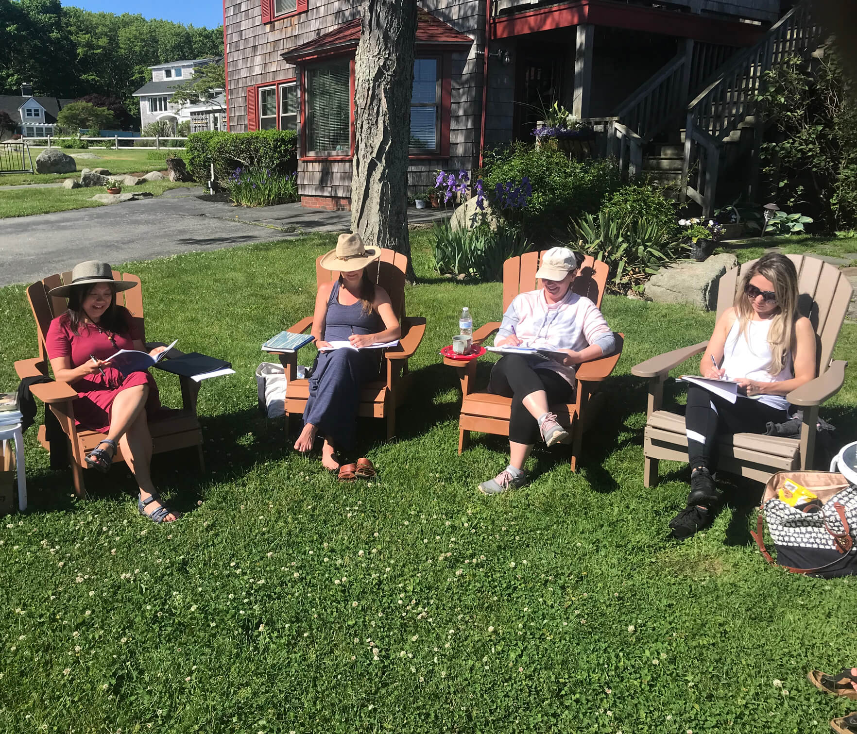 Judy Chow and three retreat attendees sitting on Adirondack chairs sharing their writing