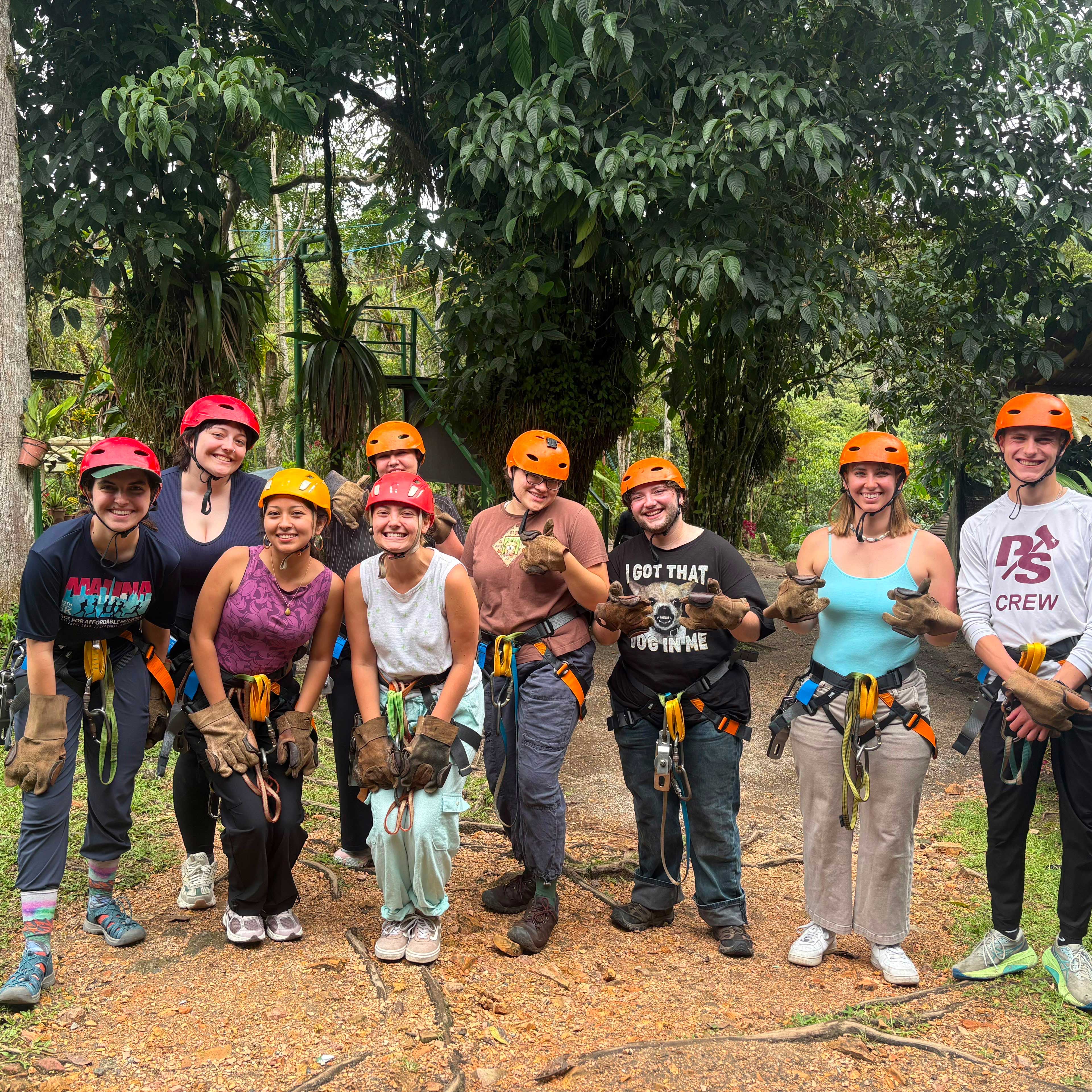 Julia stands with several other students after zip-lining in the Amazon rainforest. They wear safety helmets and harnesses. 
