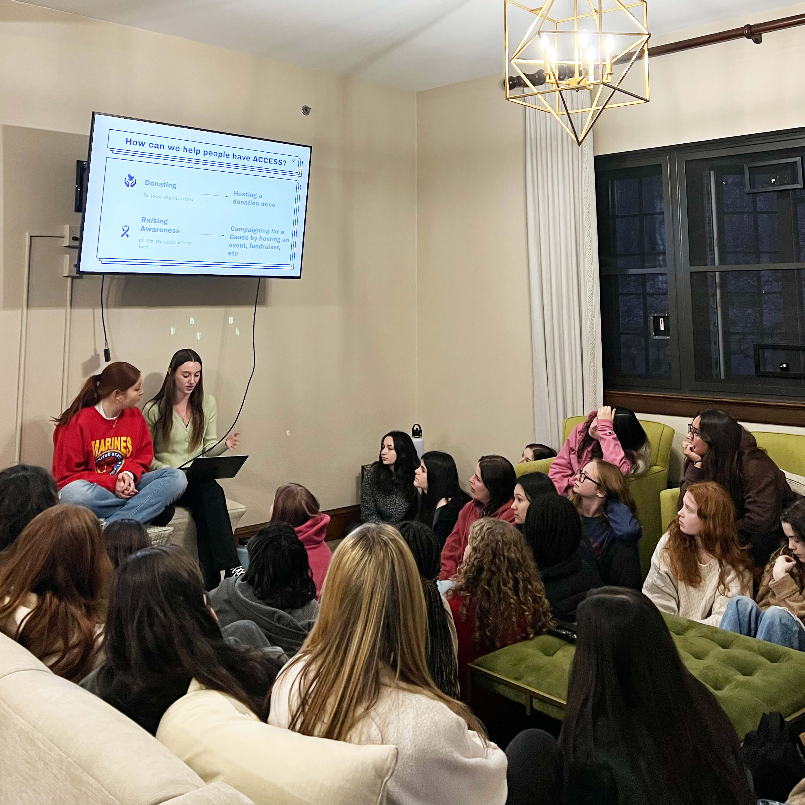 Kappa Delta sisters lead a brainstorming session with girl scouts who sit around them on the floor and on couches.