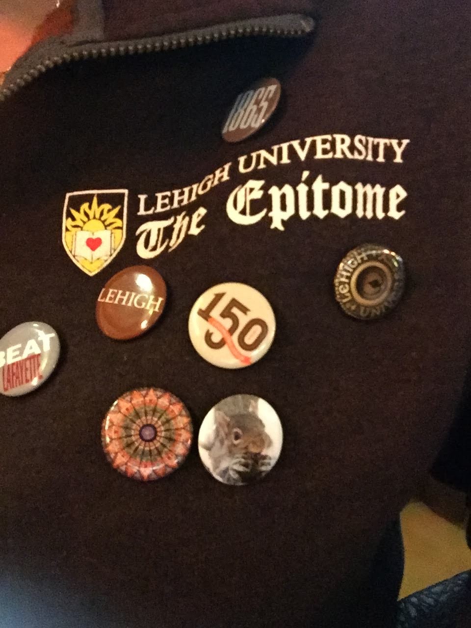 Katherine's brown sweater is Epitome branded and features a slew of pins. Among them is a pin for the 150th year of Lehigh.