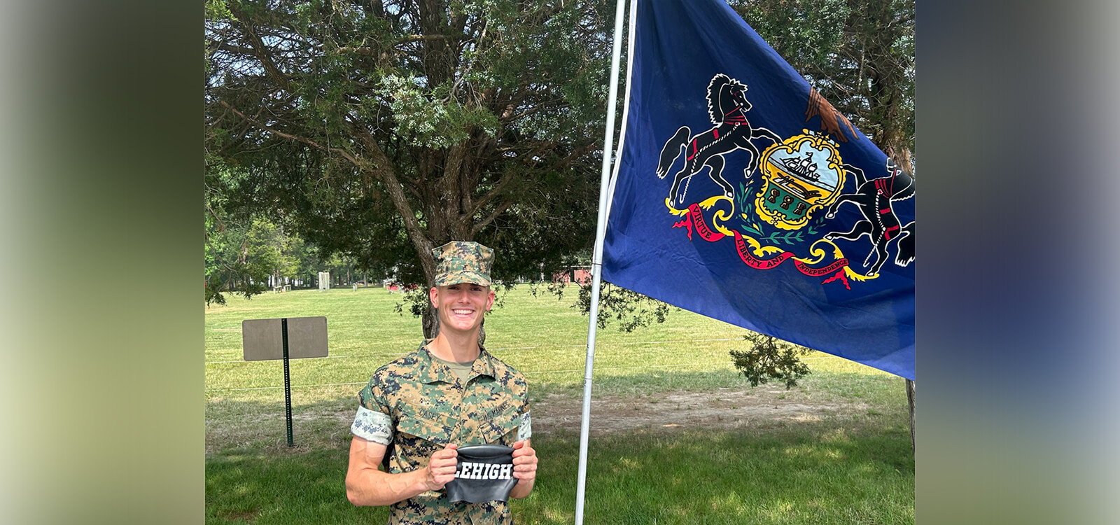 Keagan Casey in fatigues stands before a Marine flag