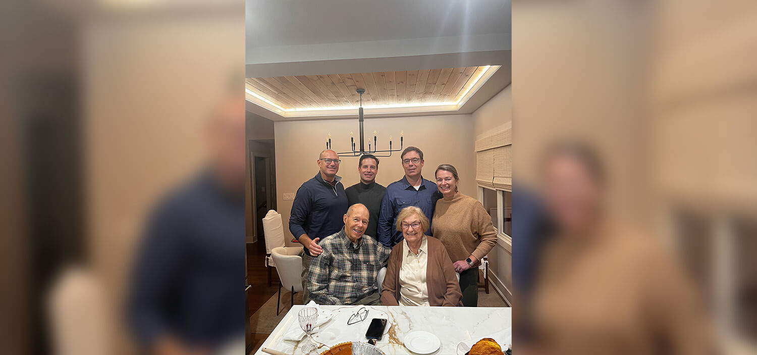 A family of six smile for the camera together at a dinner table.