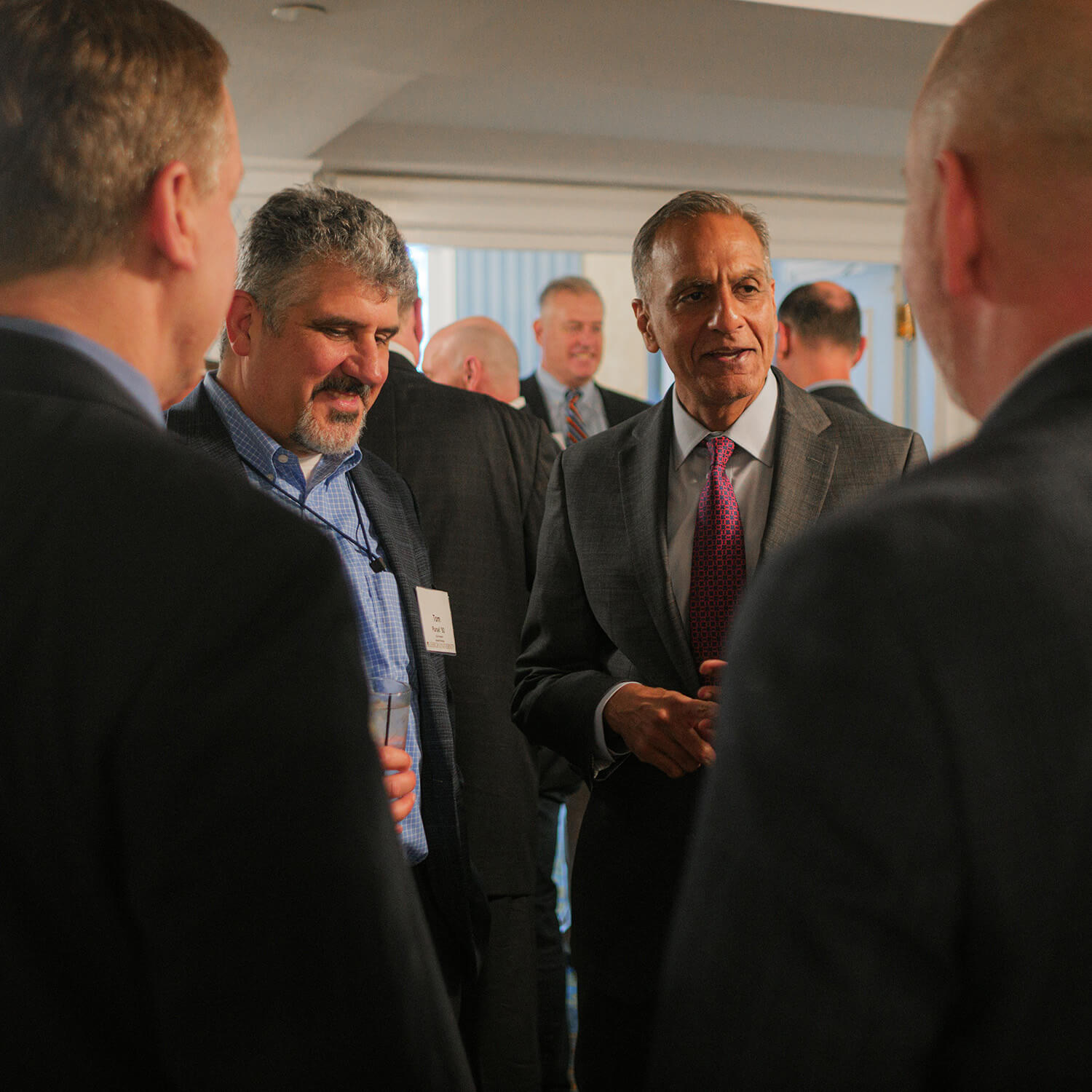 Richard Verma stands with three other alumni in discussion at the event.