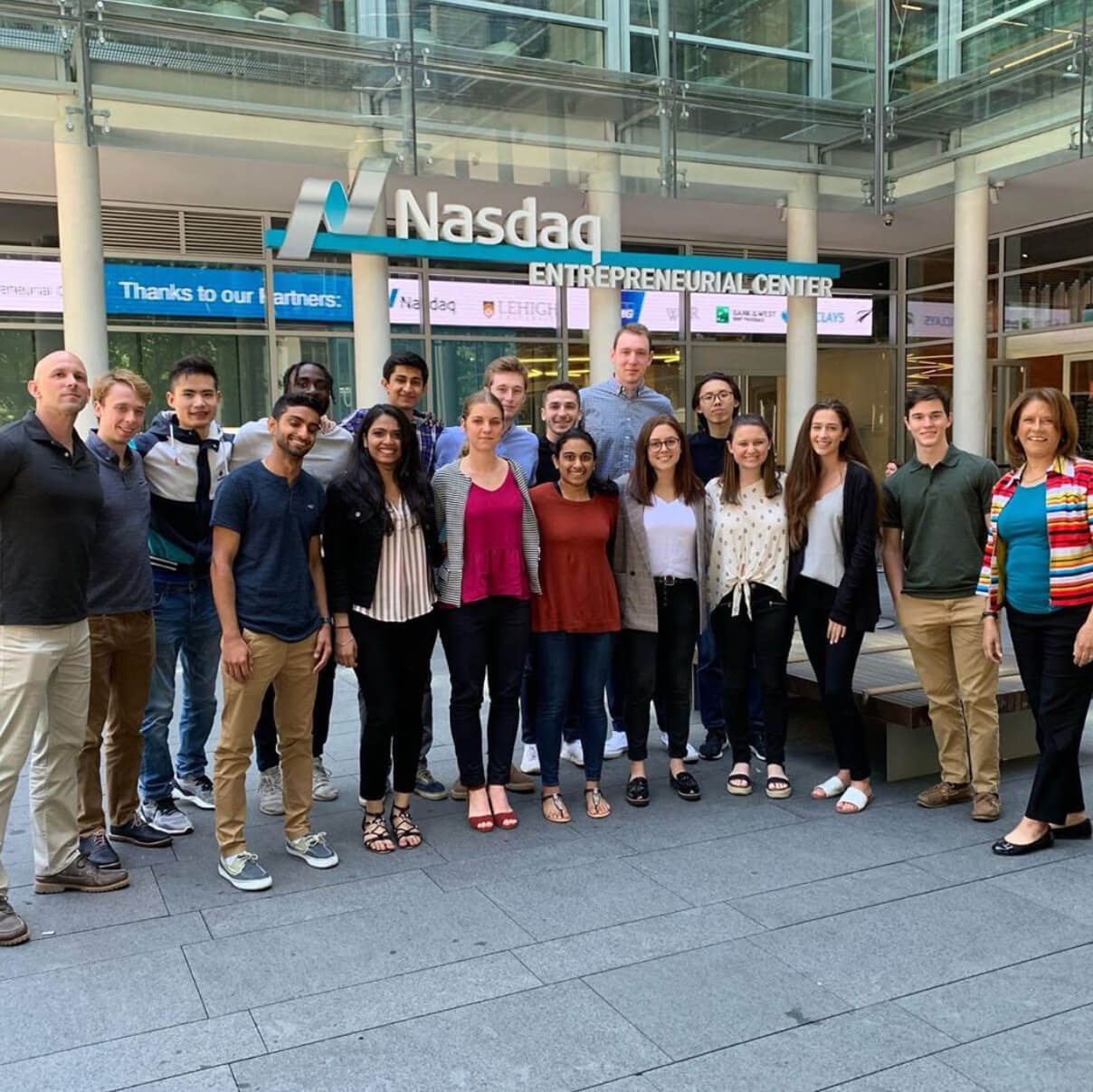 Kaja Skerlj poses with a large group of fellow students in front of a Nasdaq sign.