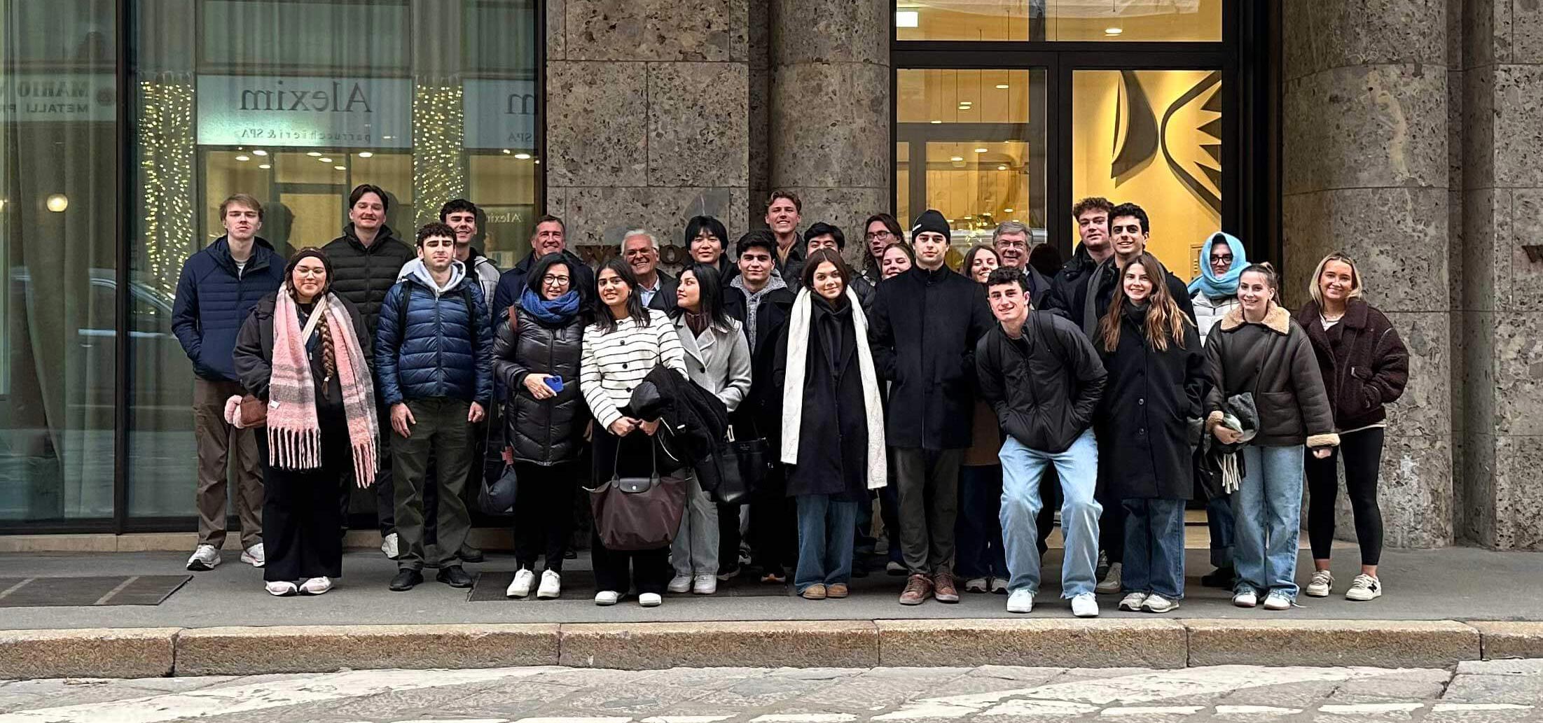 Lucia and a group of students minoring in real estate stand together in thick puffer jackers and smile.