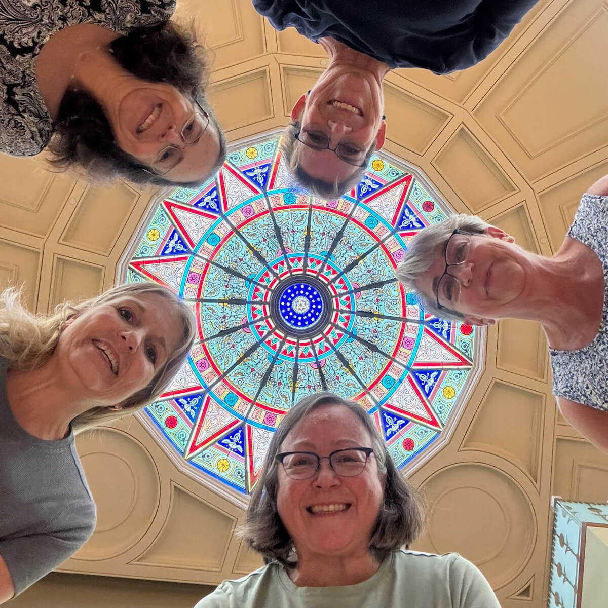 5 women look down into a camera shooting from the floor and looking up at the rotunda in Linderman Library.