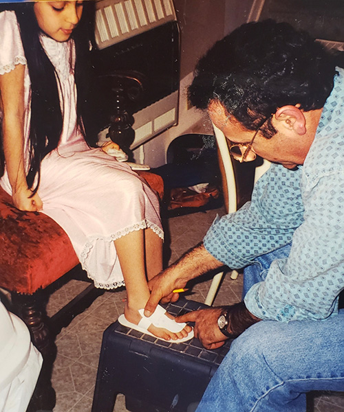 Mansour measures a white sandal on a girl's foot