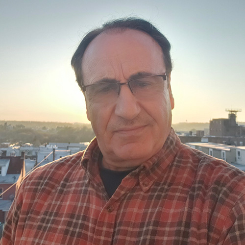 Mansour Mansour in plaid on a rooftop at sunset