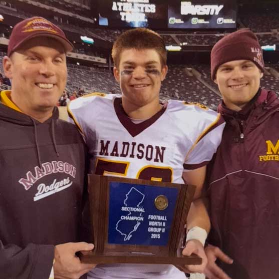 Marty stands with his sons, Shane and Martin, after winning a championship game. They each wear Madison football merch.