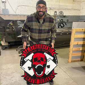 Manraj Matharu with a red skull and playing cards logo made in his fabrication shop