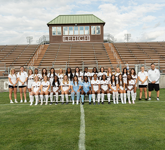 Women's team with coaches pose for team photo in stadium