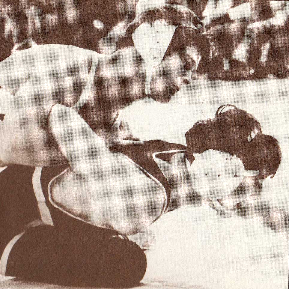 A black and white photograph depicts Michael in the middle of a wrestling match. Michael pins his opponent, who tries to get free.