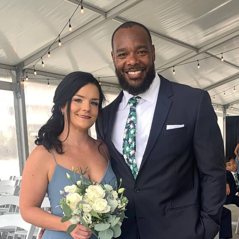Mo Taylor and his wife, CJ, dressed formally and smiling together under a string-lit tent at a celebration.