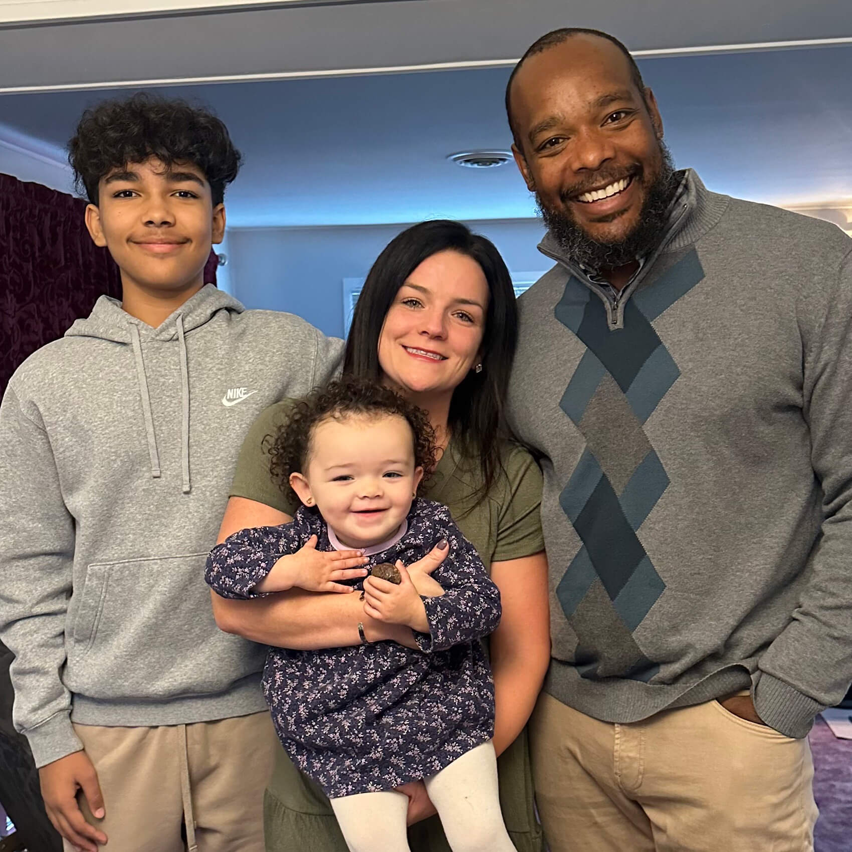 Mo Taylor poses at home with his wife, CJ, their teenage son Isaiah, and baby daughter Tessa, who beams in her mom’s arms.