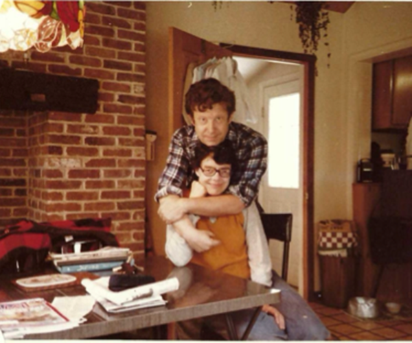 Ned hugs Linda in their kitchen at home.