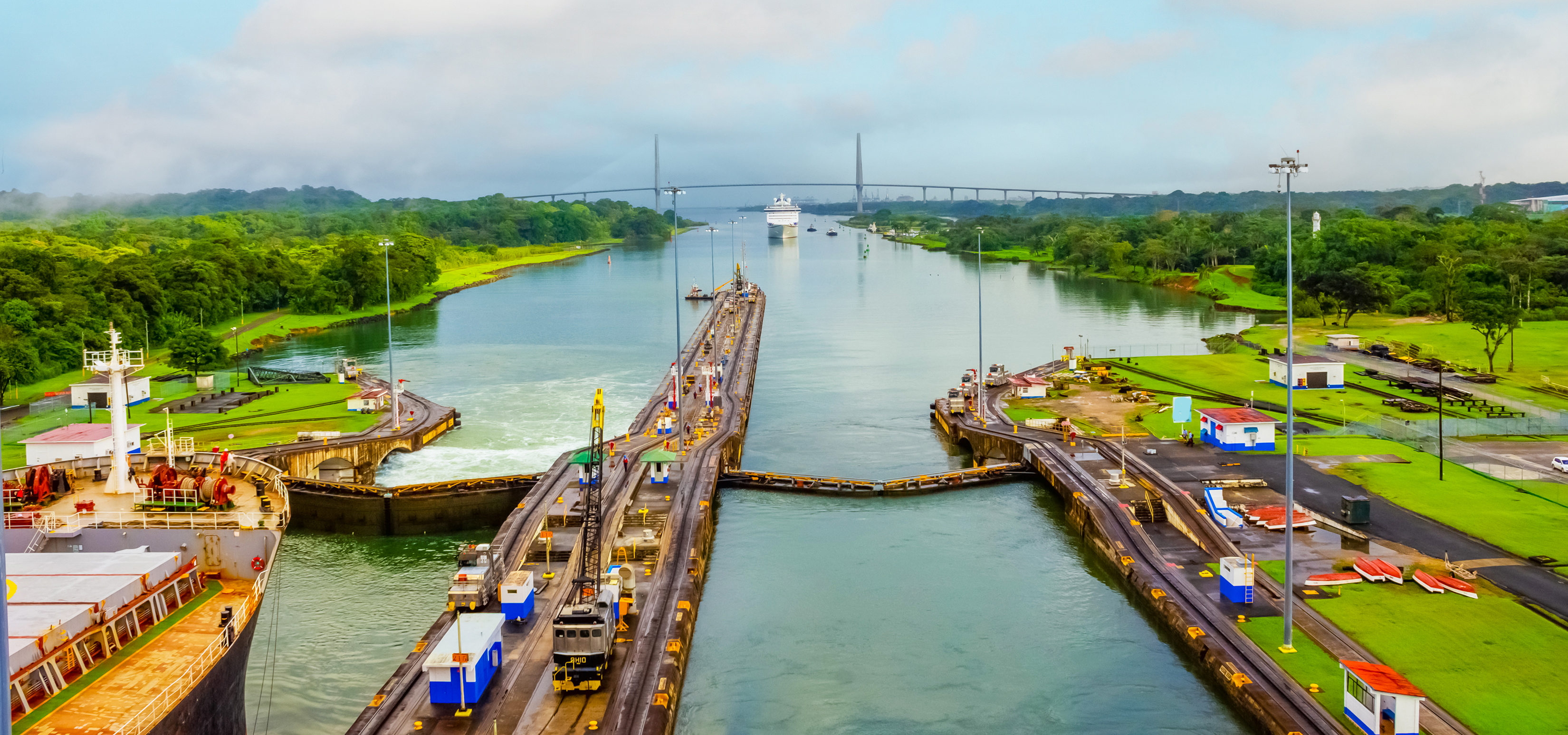 The Panama Canal framed by lush green grass and colorful buildings.