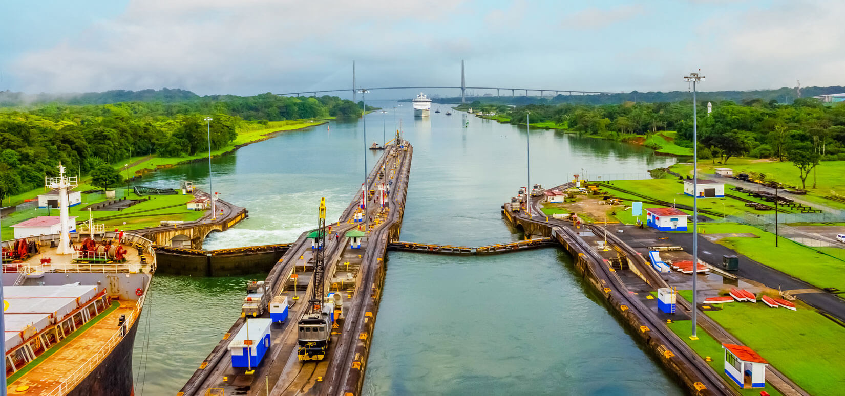 A gate along the Panama Canal lined on either side with trees.